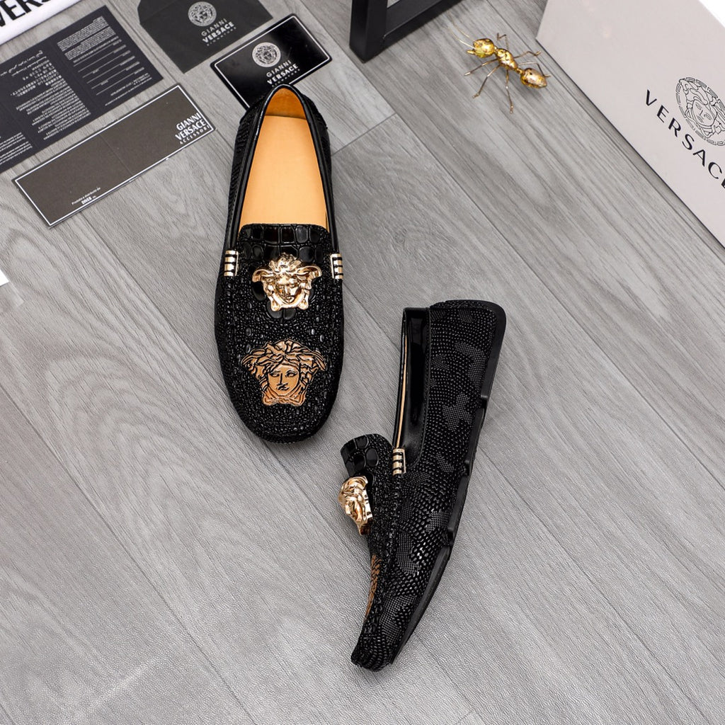 Black loafers pair, one upside view, gold-tone emblem on textured vamp