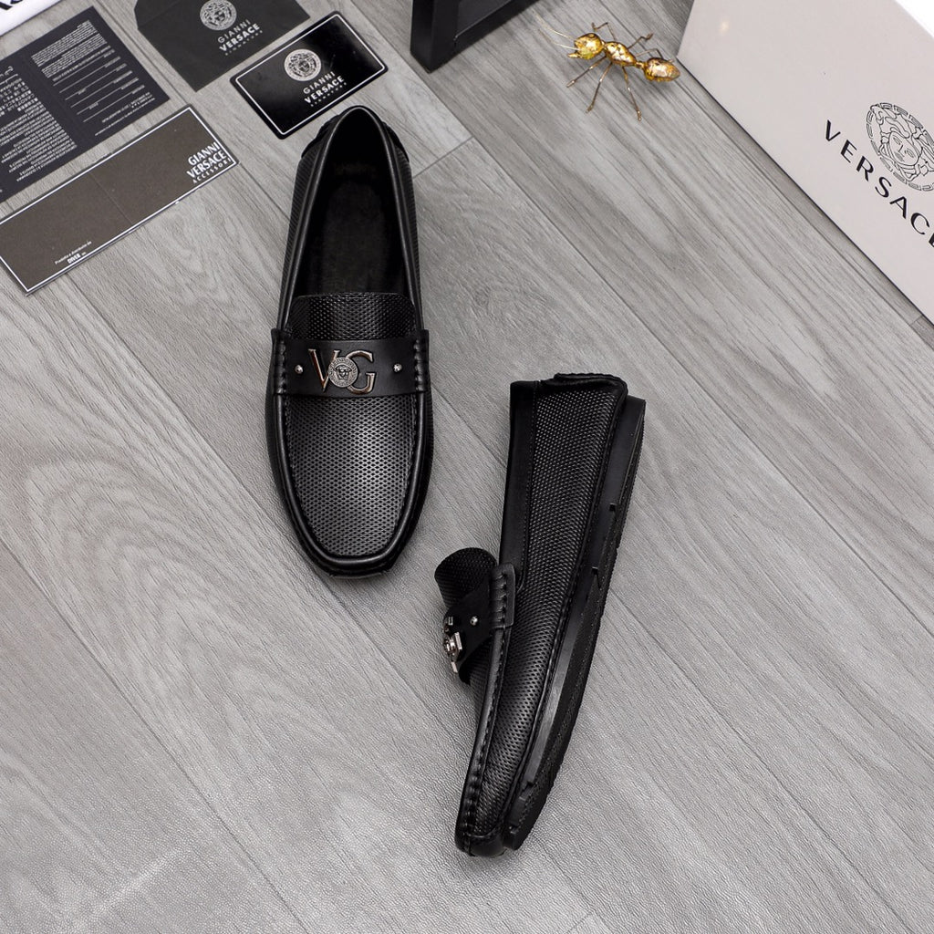 Versace black slip-on loafers pair, one standing upright with front buckle
