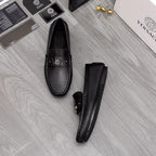 Versace black slip-on loafers pair, one standing upright with front buckle