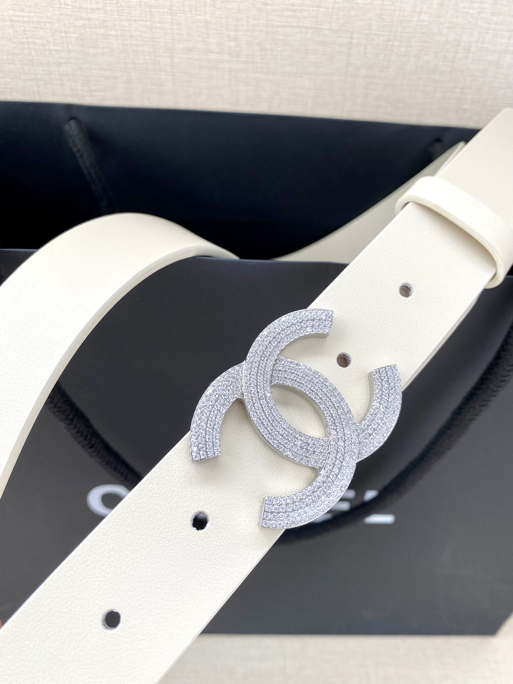 Chanel belt close-up: light cream strap with perforations and glitter CC buckle