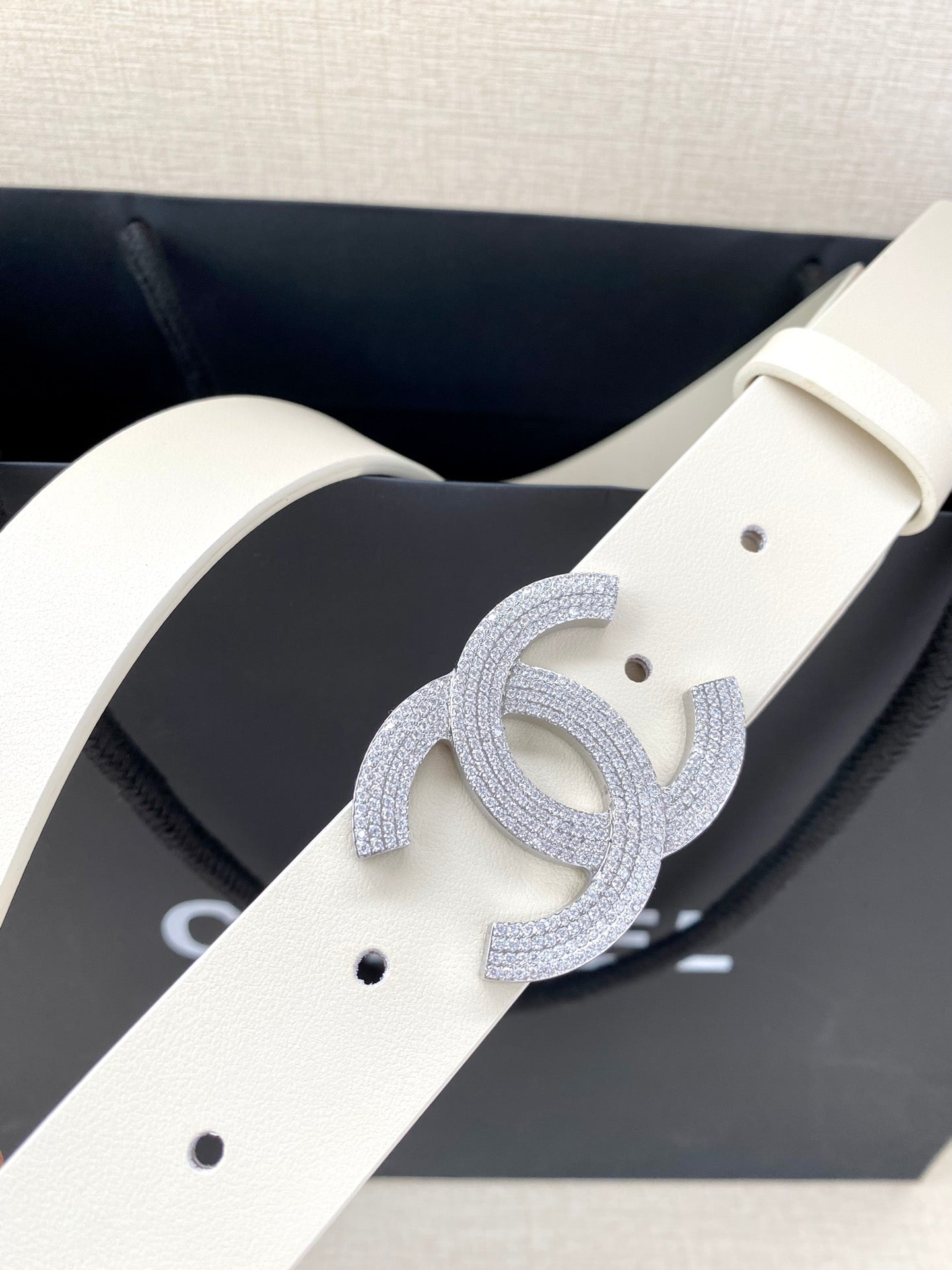 Chanel belt close-up: light cream strap with perforations and glitter CC buckle