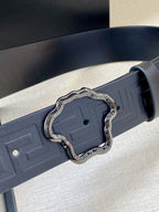 Close-up designer belt in dark navy with embossed texture and silver ornate buckle