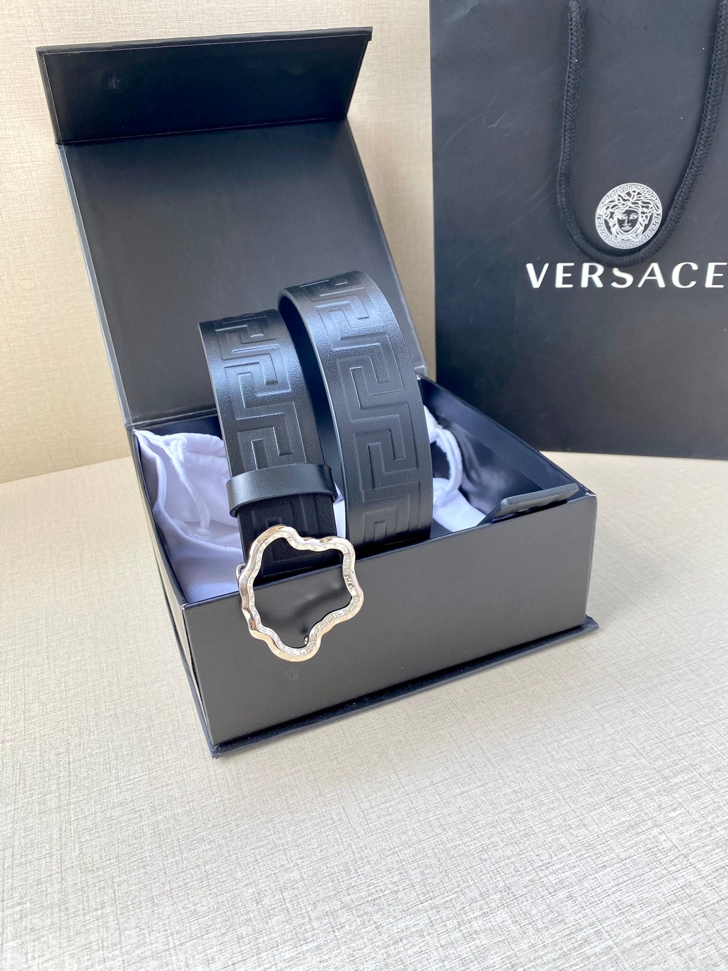 Designer belt in gift box with dark navy embossed strap and small gold buckle