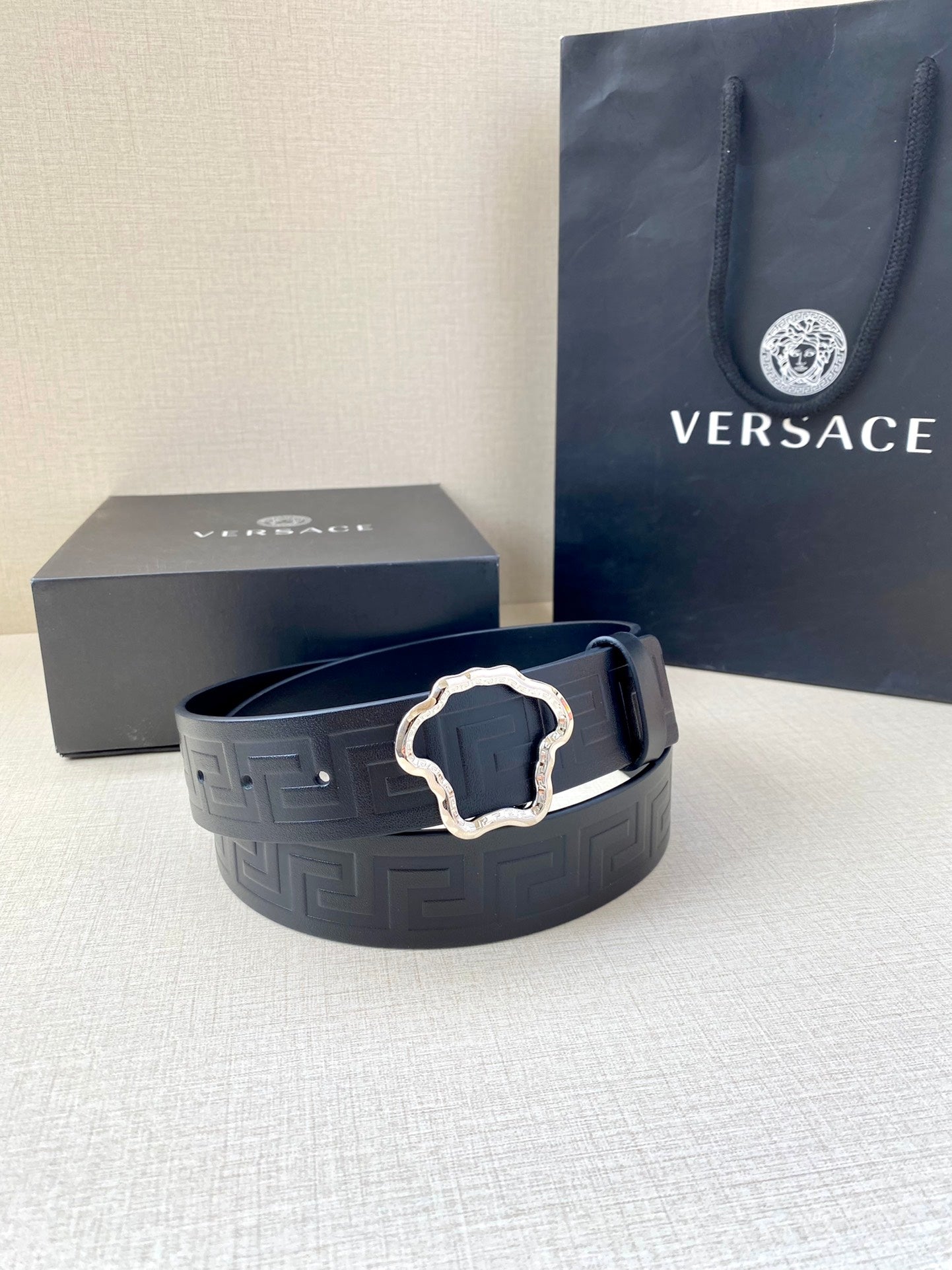 Designer belt in dark navy with embossed pattern and gold ornate buckle on display