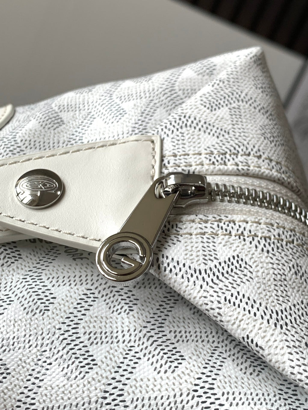 Goyard monogram clutch bag detail: snap button and D-ring on zip pull