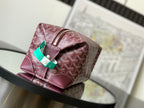 Goyard monogram bag with burgundy patterned canvas, top zip, and green accent tab
