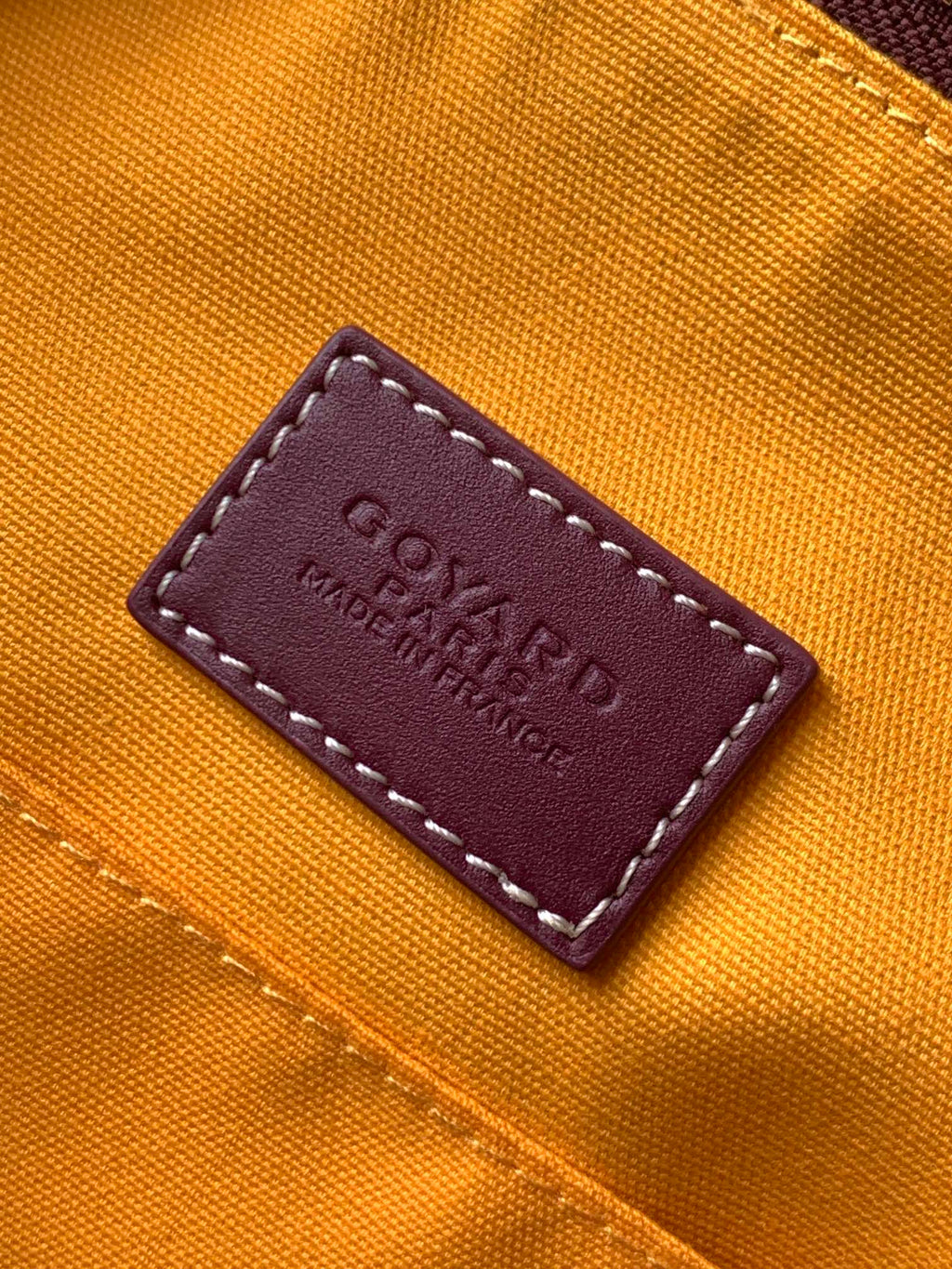 Goyard bag leather brand label on orange fabric reading “Goyard” and “Made in France”
