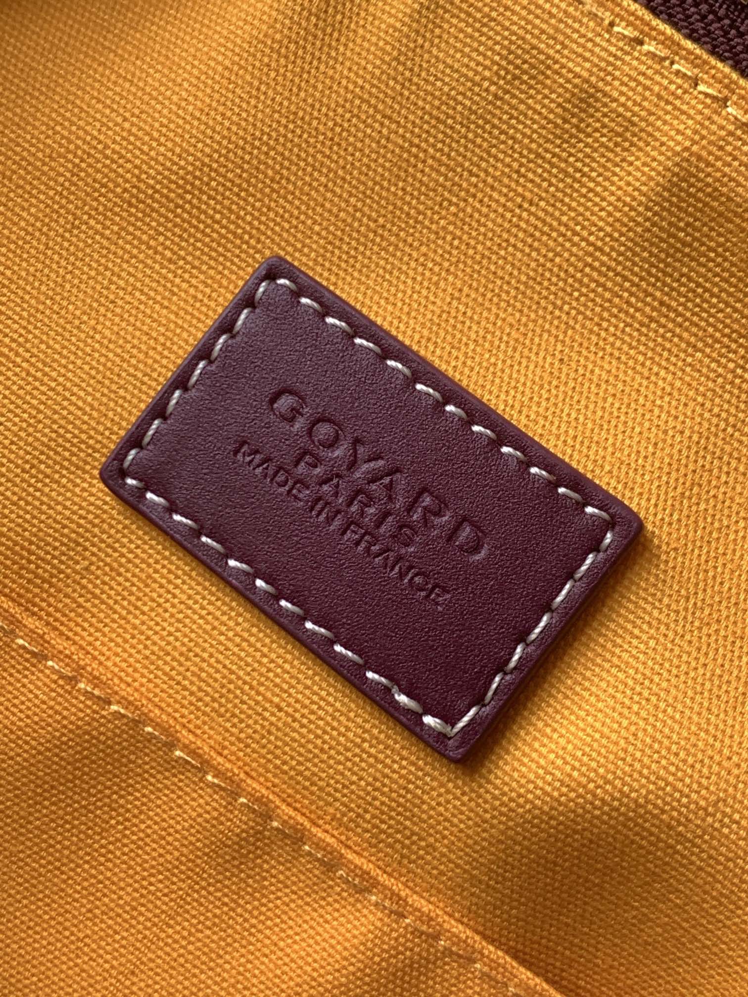 Goyard bag leather brand label on orange fabric reading “Goyard” and “Made in France”
