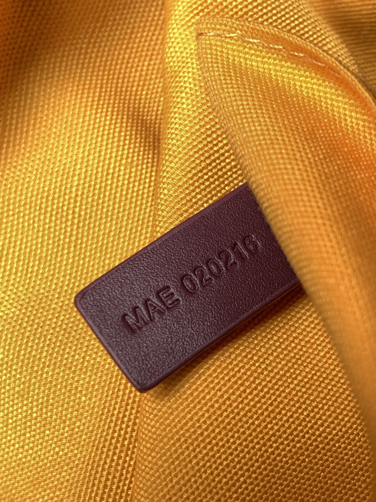 Goyard bag leather tag on orange fabric reading “MADE IN UAE 032124”