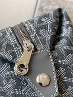 Dark gray patterned bag closeup with silver ring hardware and smooth gray pocket patch