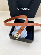 Tan leather belt with gold-tone CC logo buckle, partly inside the box