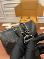 Louis Vuitton monogram duffel handle with silver D-ring clasp, held in black gloves.