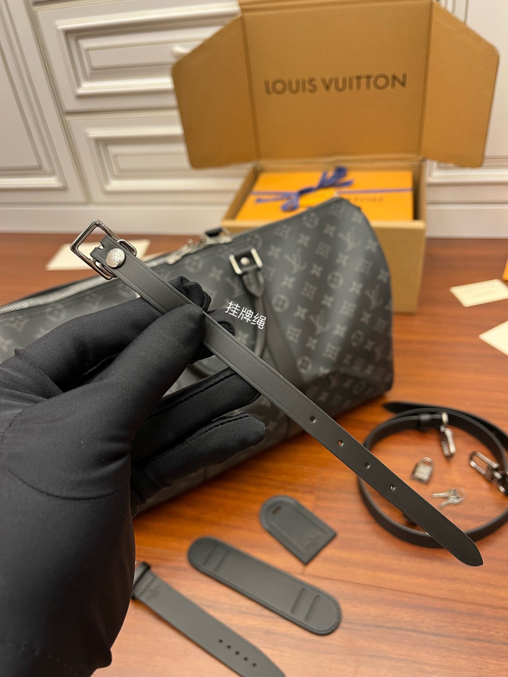 Louis Vuitton monogram duffel with black leather strap and small accessory tags, close-up.