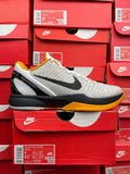 White and yellow athletic sneaker with black swoosh, textured knit upper, white laces
