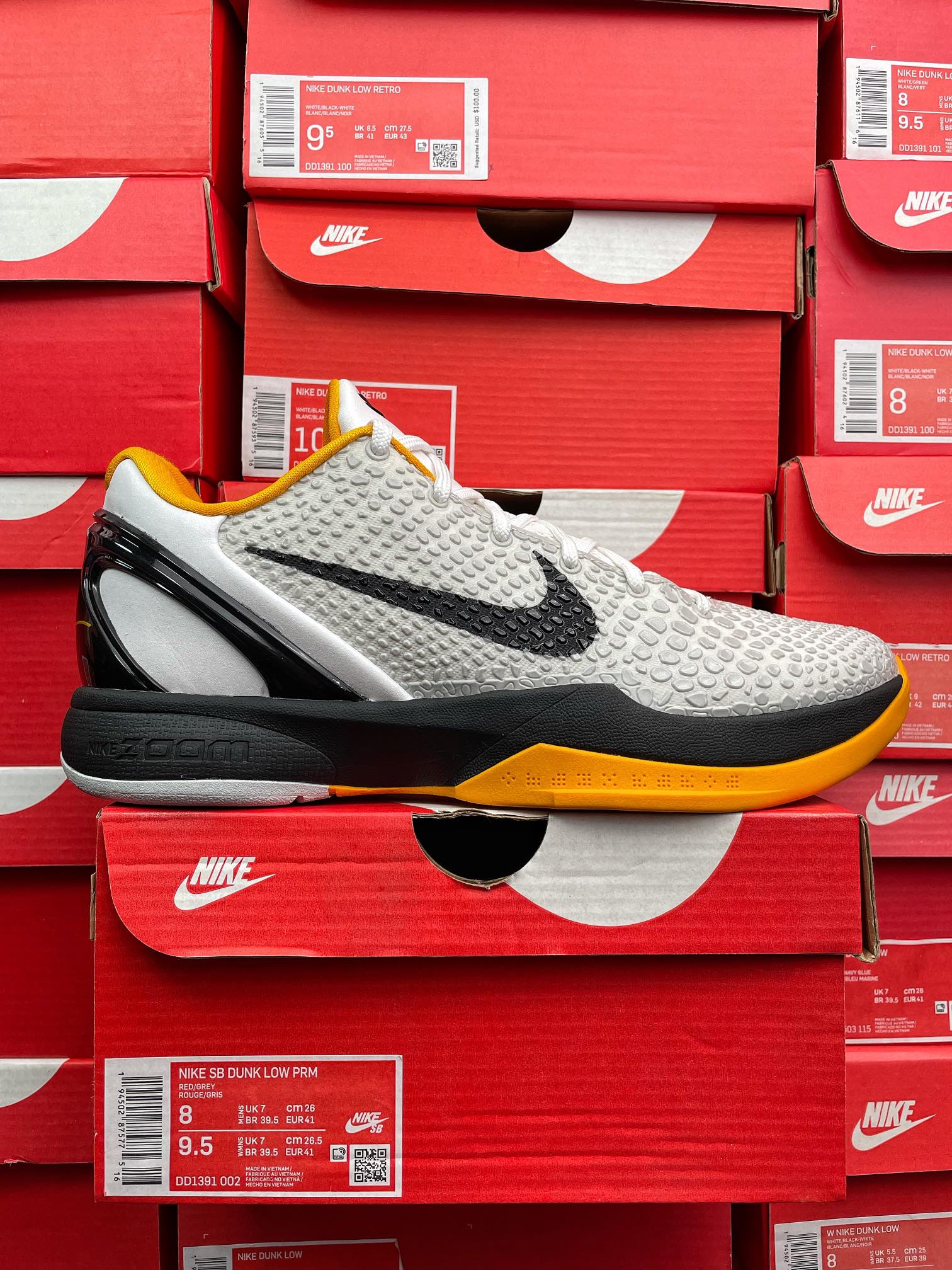 White and yellow athletic sneaker with black swoosh, textured knit upper, white laces