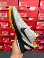 Side view of white athletic sneaker with yellow outsole edge, black sole, textured upper