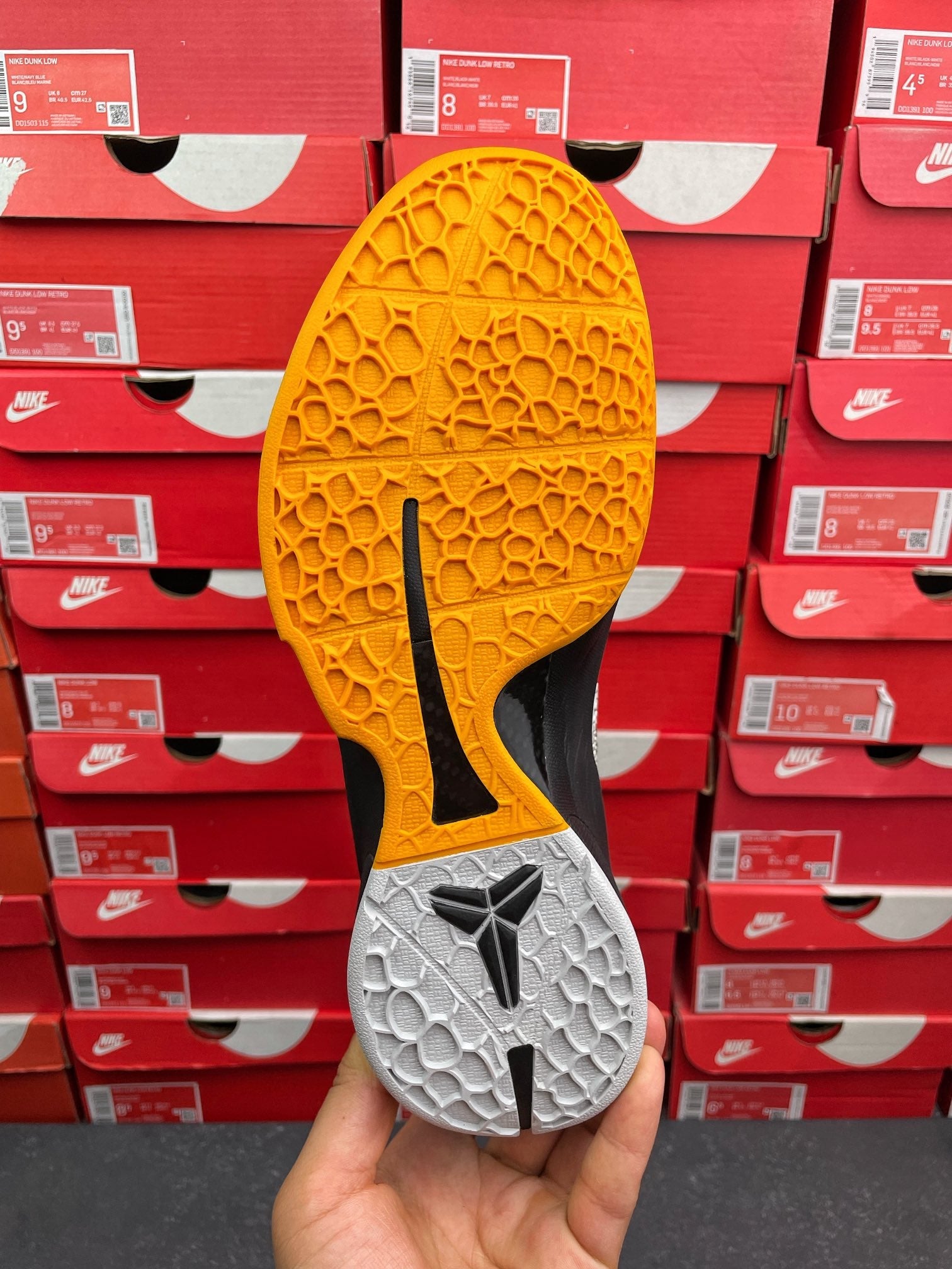 Yellow and gray outsole of athletic sneaker with traction pods and black logo on rubber