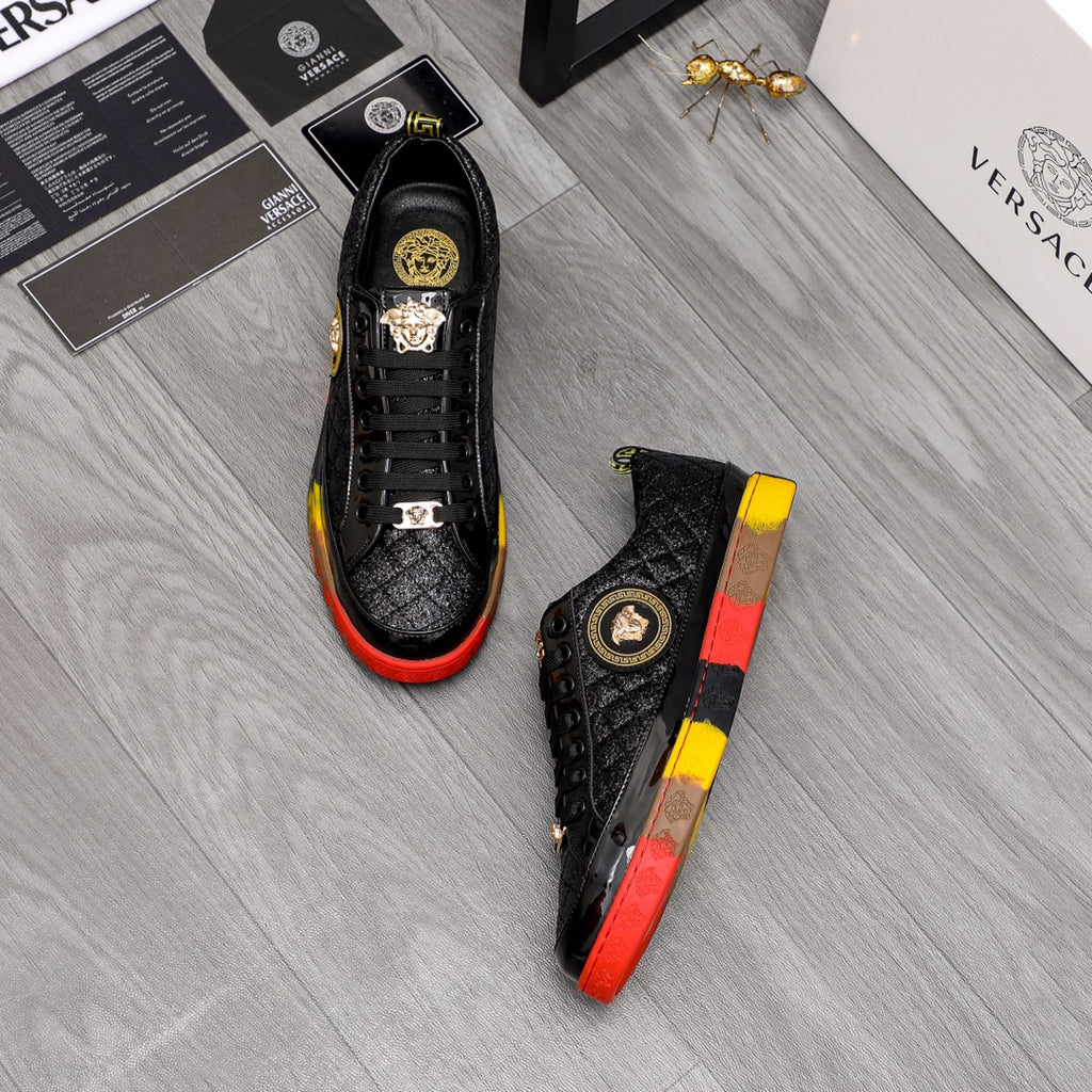 Pair of black lace-up sneakers with gold details and red/yellow contrast soles