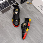 Pair of black lace-up sneakers with gold details and red/yellow contrast soles