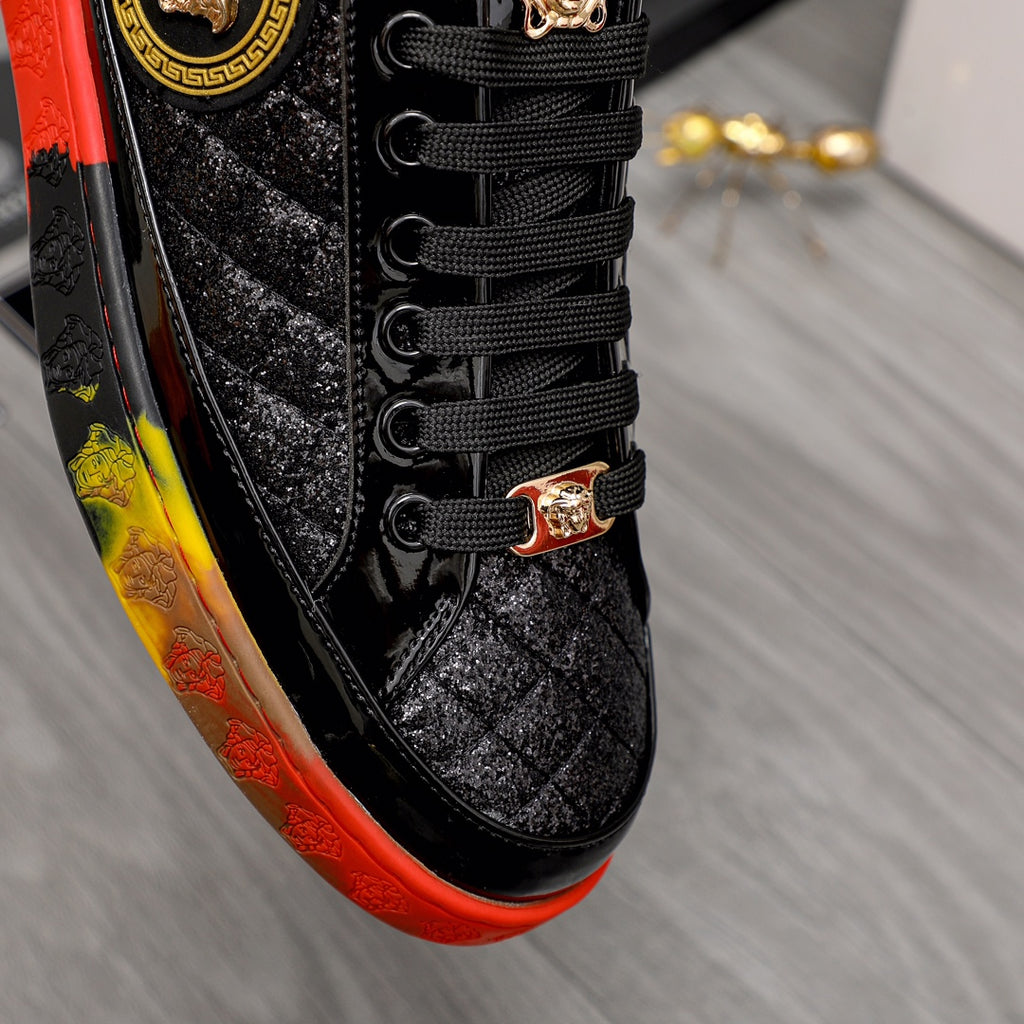 Close-up of black lace-up sneaker with gold buckle detail and red/yellow edge