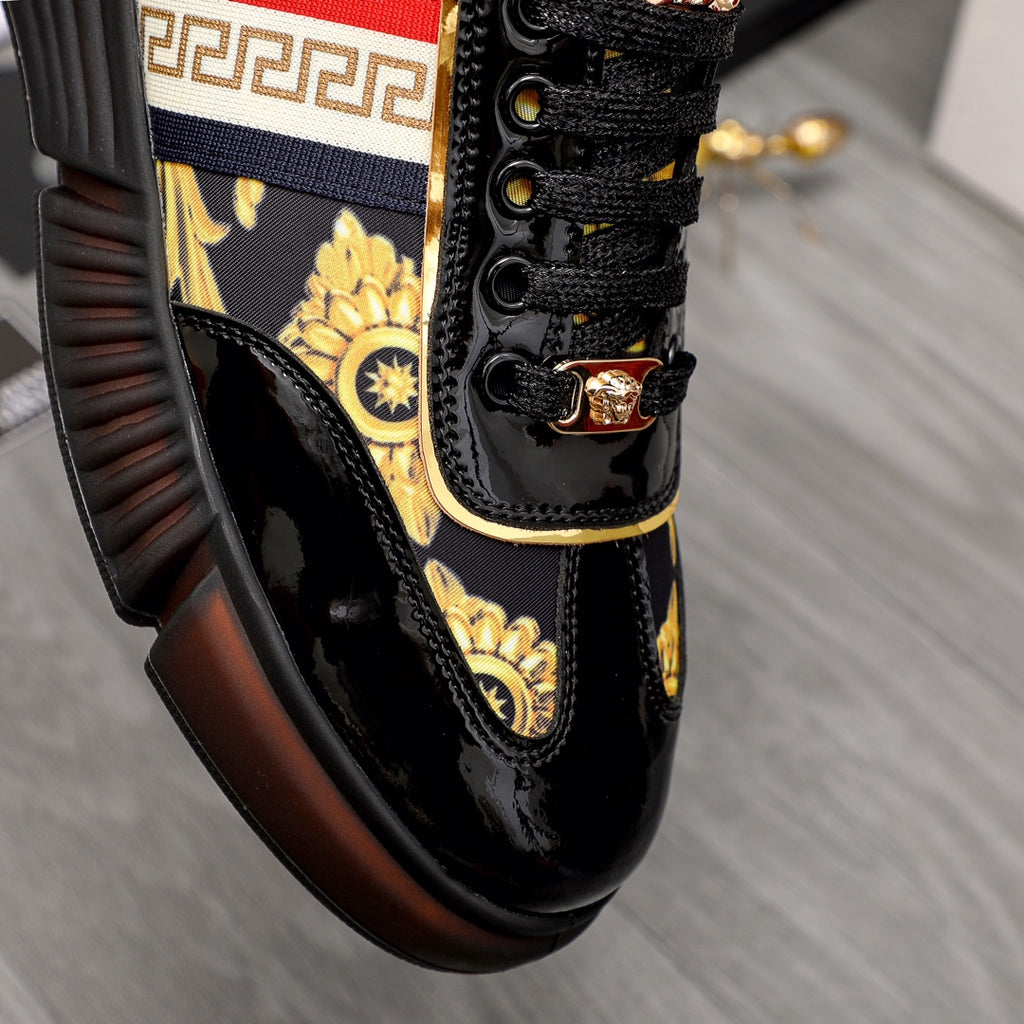 Versace luxury sneaker close-up, black laces with gold emblem and red/white stripe trim.