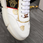 Versace white sneaker side with gold lace charm, emblem patch, and logo stripe