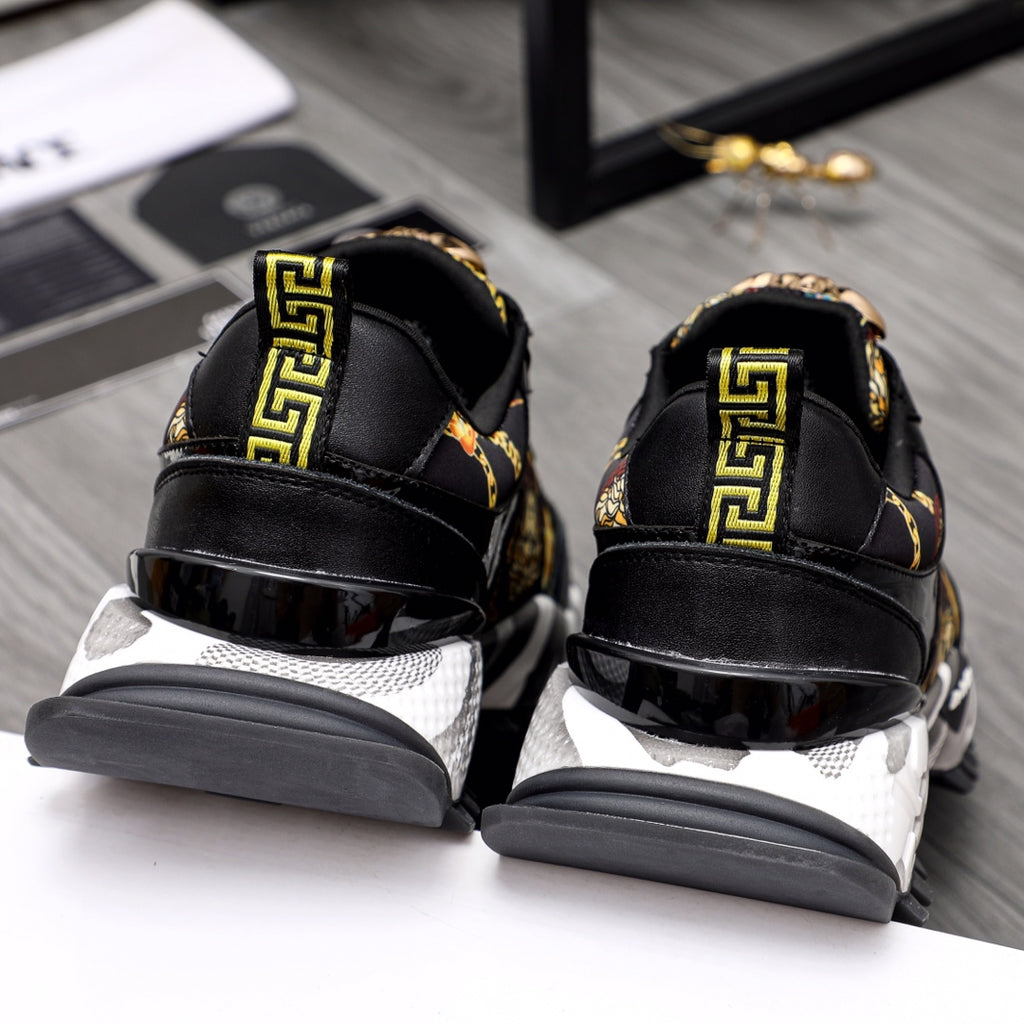 Black leather sneakers with gold Greek key trim at heel and chunky white sole