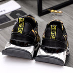Black leather sneakers with gold Greek key trim at heel and chunky white sole