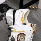 White sneaker side view with gold Medusa hardware, patterned panel, chunky sole