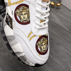 Close-up of white sneaker with gold Medusa motif, multicolor emblem trim, white laces