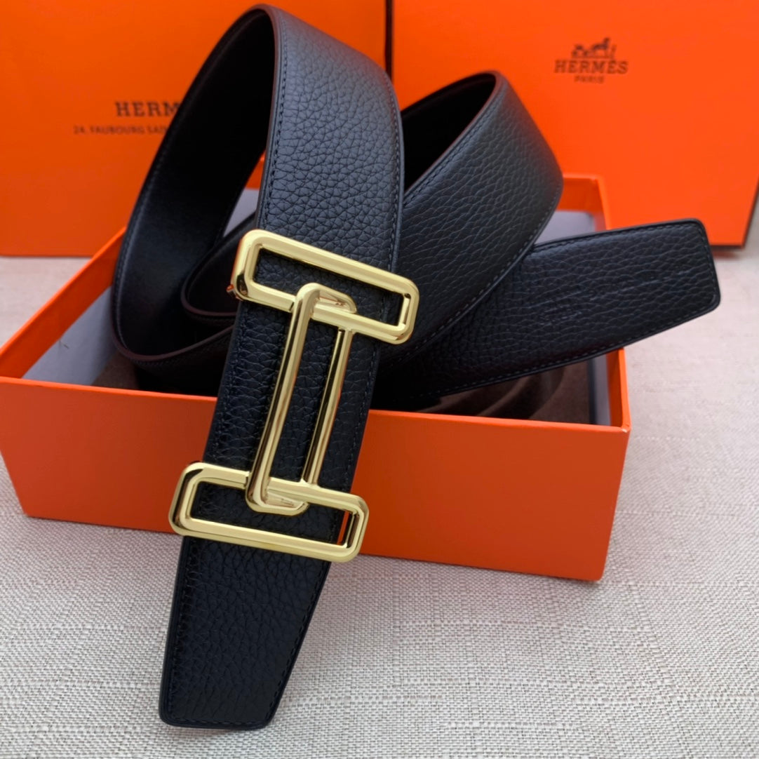 Leather belt with dark navy grain texture and gold-tone double H buckle, looped.
