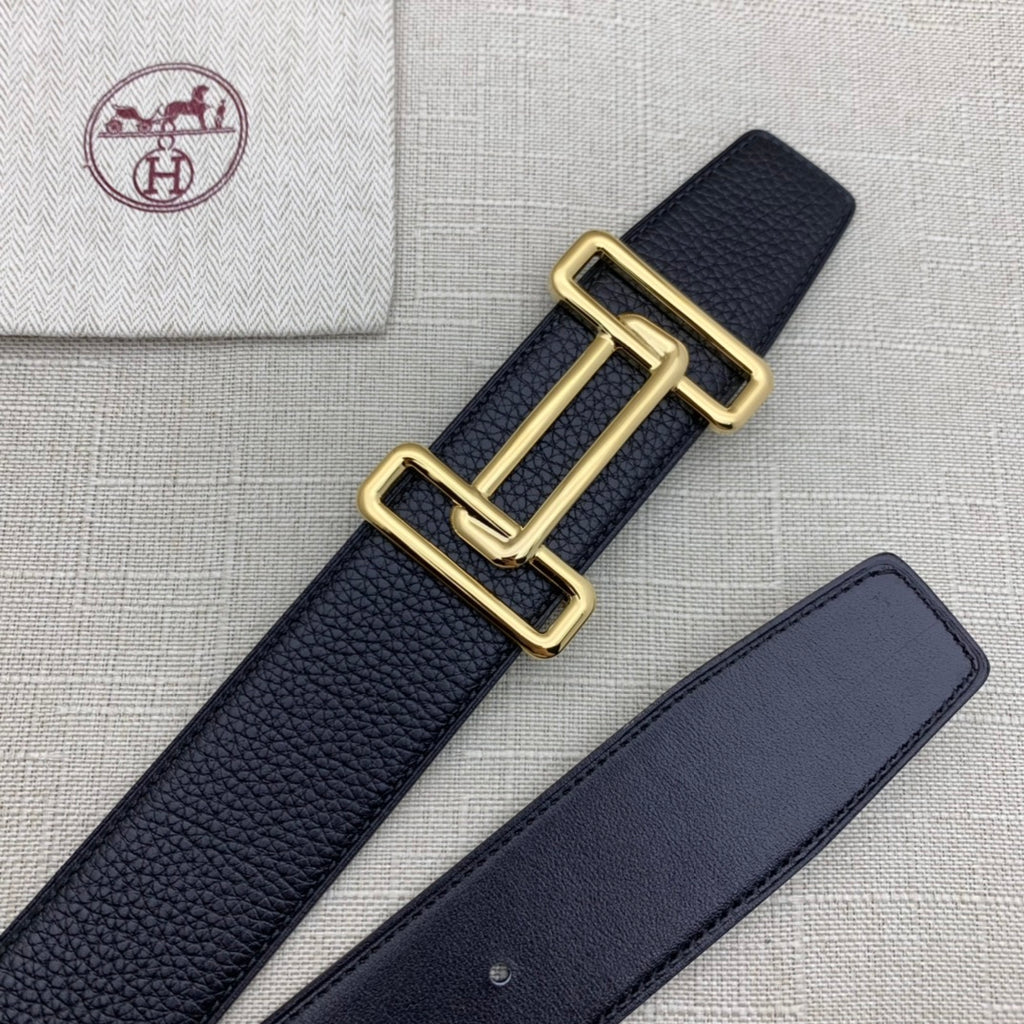 Leather belt with dark navy grain texture and gold-tone double H buckle beside strap.