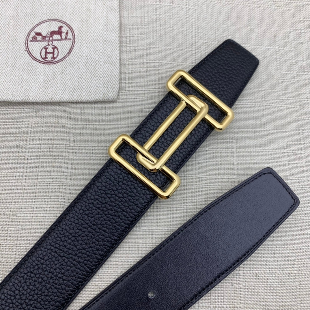 Leather belt with dark navy grain texture and gold-tone double H buckle beside strap.