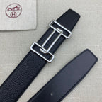 Leather belt with dark navy grain texture and silver-tone double H buckle beside strap.