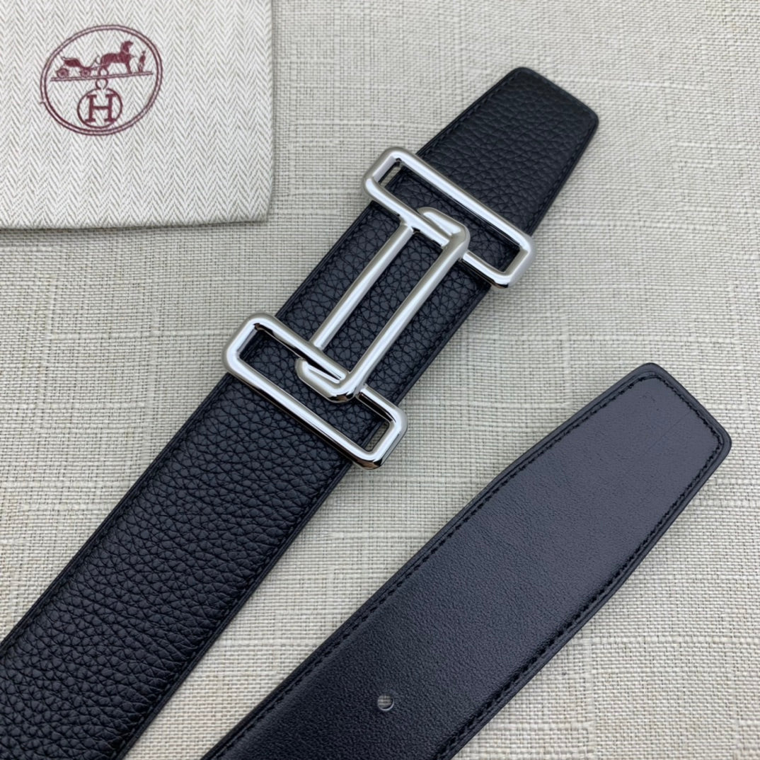 Leather belt with dark navy grain texture and silver-tone double H buckle beside strap.
