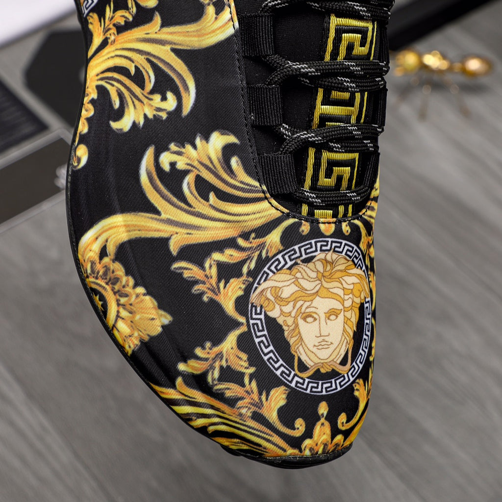 Close-up black luxury sneaker with gold baroque print, Greca laces, and Medusa patch