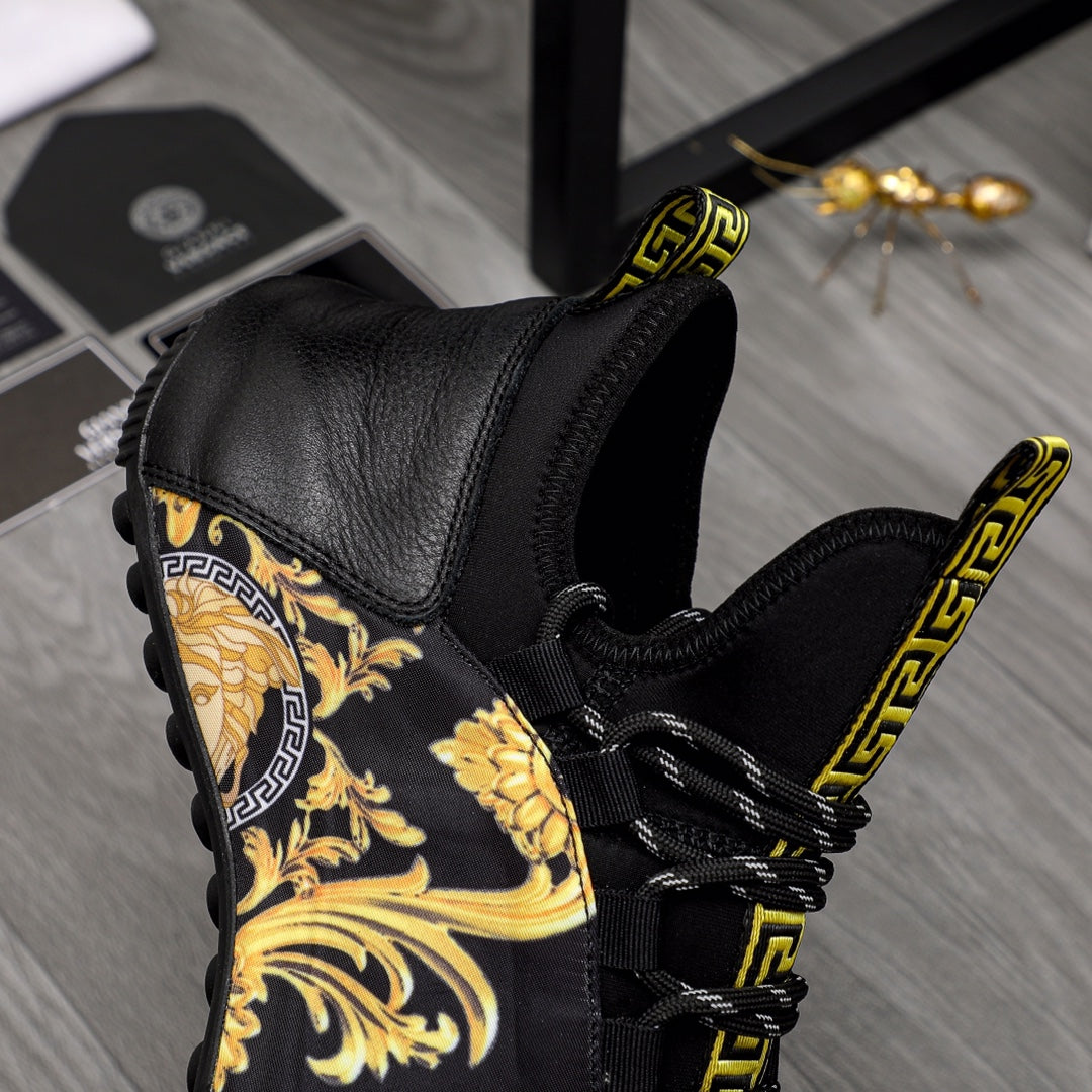 Black leather luxury sneakers with gold baroque panel, Greca lace trim, and top strap