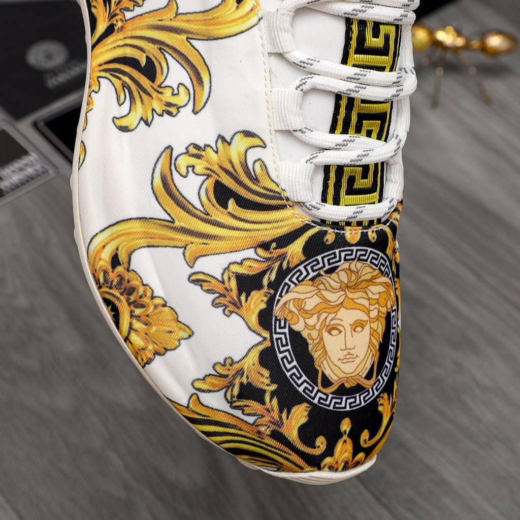 Versace sneaker toe and lace area: white base with gold baroque floral graphic and Medusa emblem