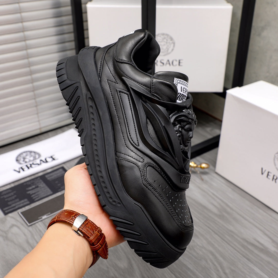 Black lace-up sneakers with textured leather panels and thick tread sole.
