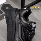Black lace-up sneakers close-up of heel and side stripes with chunky sole.