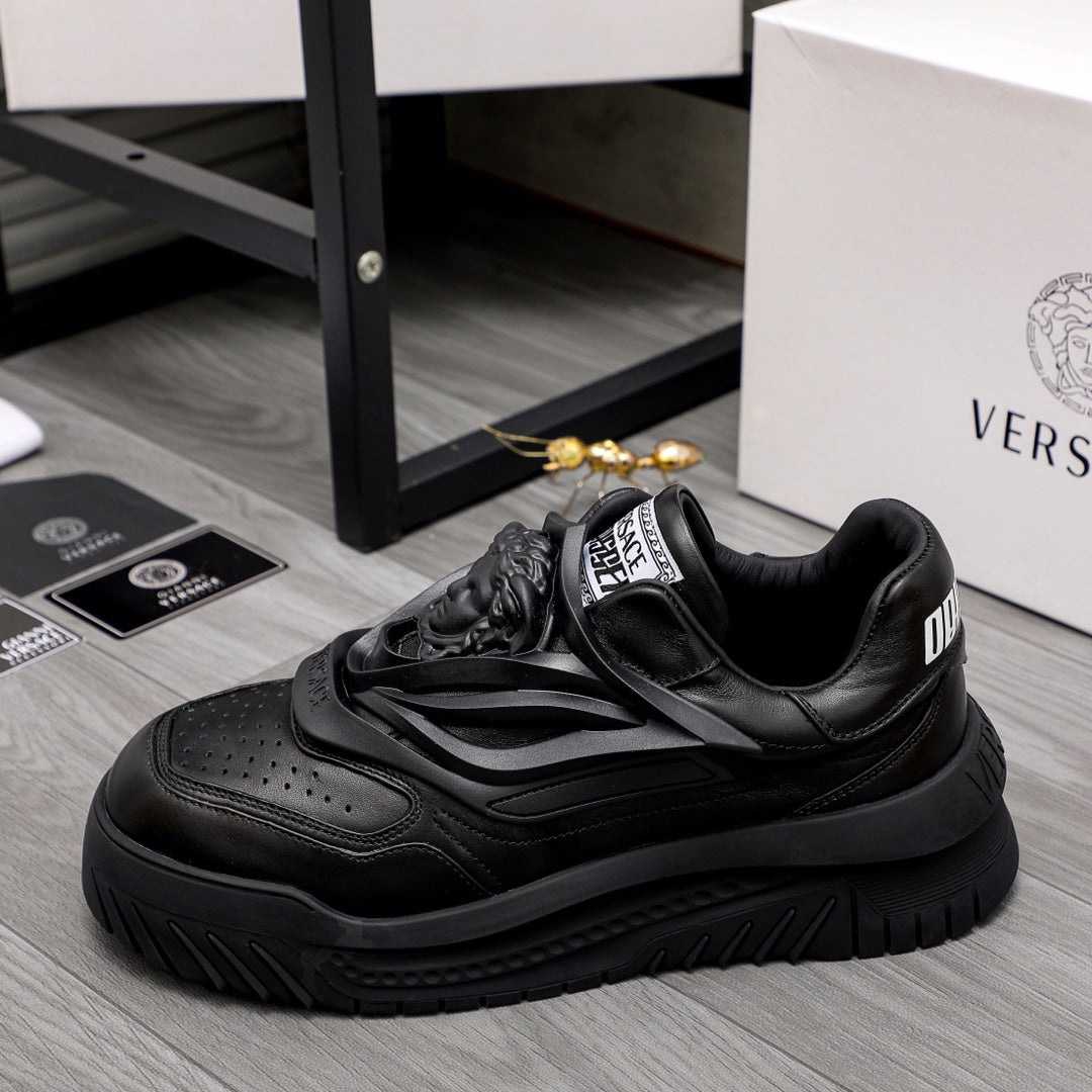 Black lace-up sneakers with layered straps and chunky rubber outsole.