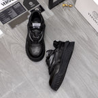 Black lace-up sneakers set with detailed toe perforations and molded sole.
