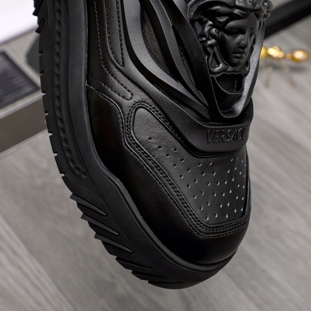 Black sneaker side view with perforated leather paneling and sculpted sole.