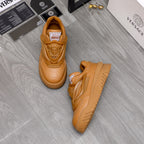 Luxury shoes: pair of tan sneakers on floor with logo tongue patches and chunky soles