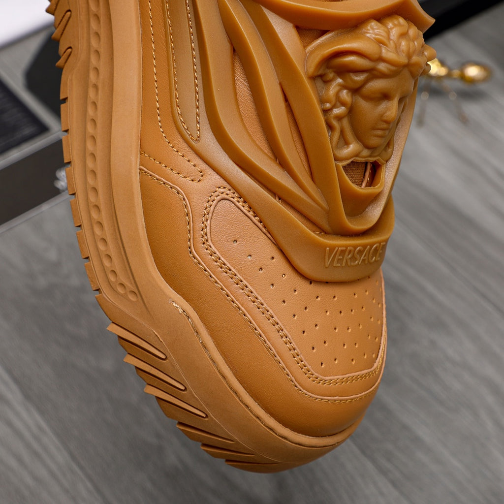 Luxury shoes: close-up of tan sneaker upper with perforations and embossed Versace logo