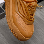Luxury shoes: close-up of tan sneaker upper with perforations and embossed Versace logo