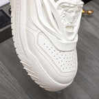 Close-up of white Versace sneakers: perforated toe, stitched panels, chunky sole.