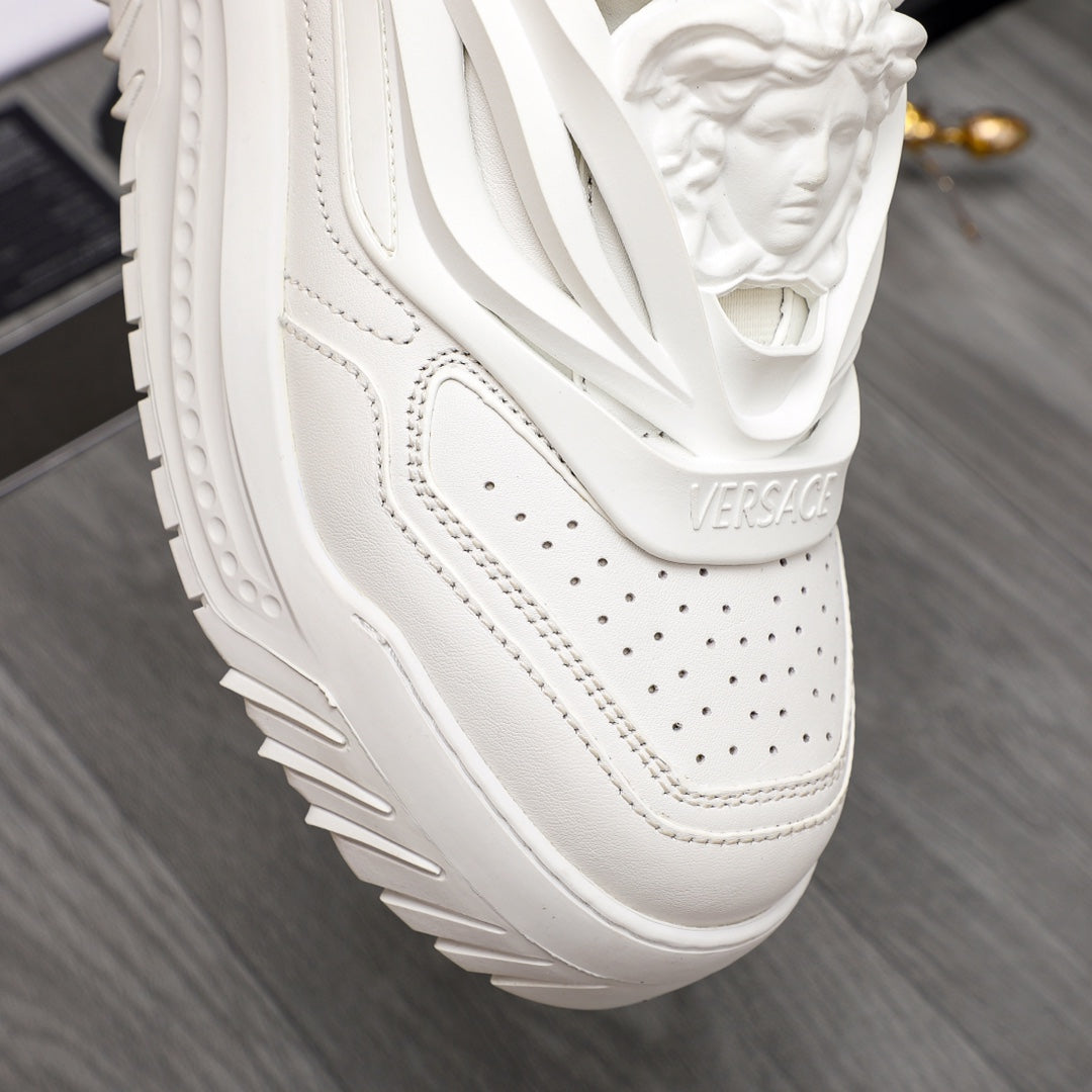 Close-up of white Versace sneakers: perforated toe, stitched panels, chunky sole.