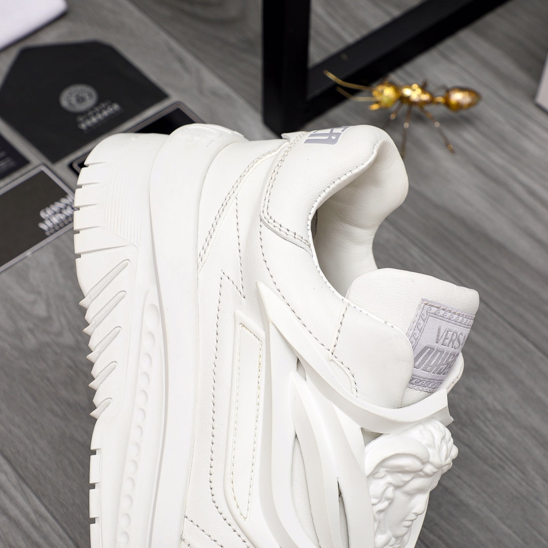 White Versace sneakers close side view, logo tab and ridged outsole details.
