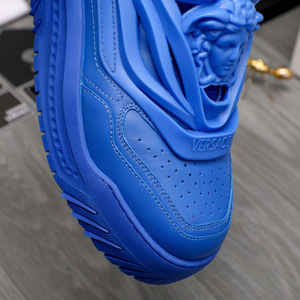 Blue leather-look sneakers close-up of molded lion-head detail and stitching